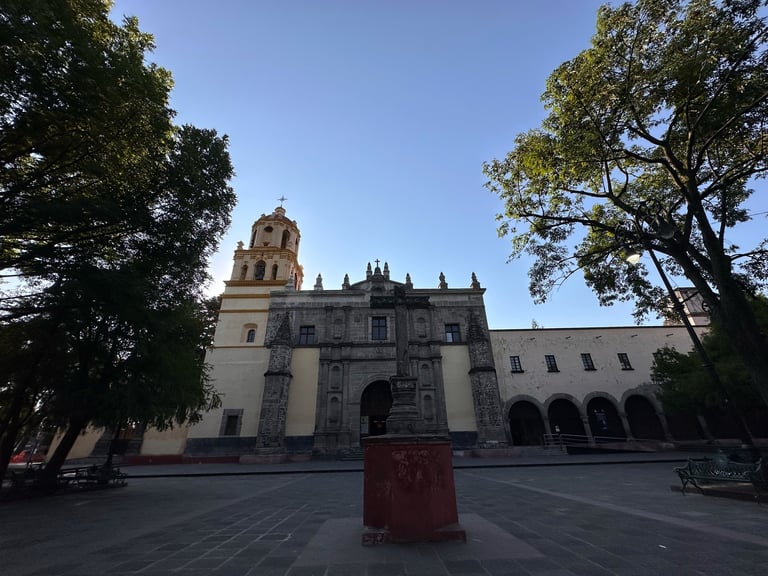 Historic colonial church facade with bell tower, stone architecture, and arched colonnade